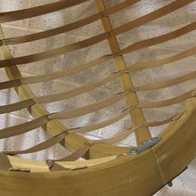 Load image into Gallery viewer, Close-up of a woven chair with a wooden frame and straps on a textured surface.
