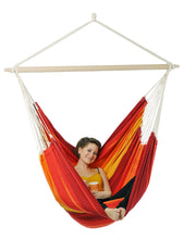 Load image into Gallery viewer, Person sitting in a red and orange hammock chair on a white background
